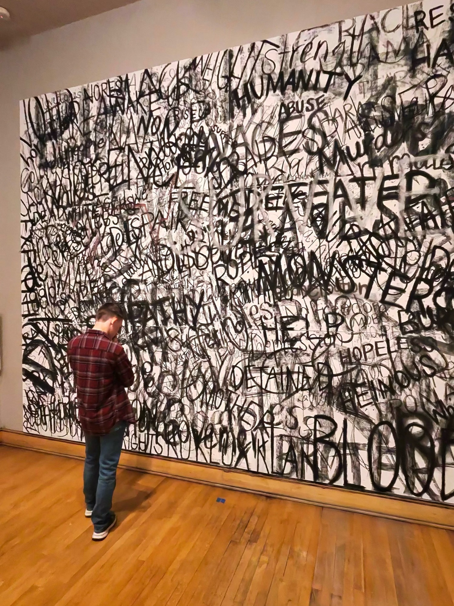 A visitor encounters Jameson Evans’s monumental black-and-white word-filled artwork, Survive